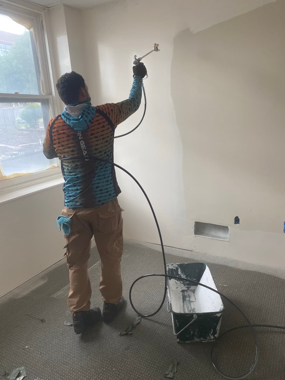 Airless sprayer laying down paint on a patched interior wall in Easton, PA